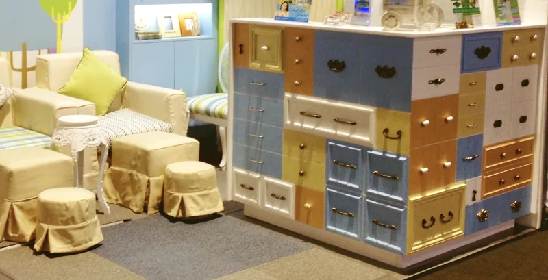 Cream sofa and footstools beside a patchwork chest of pastel drawers